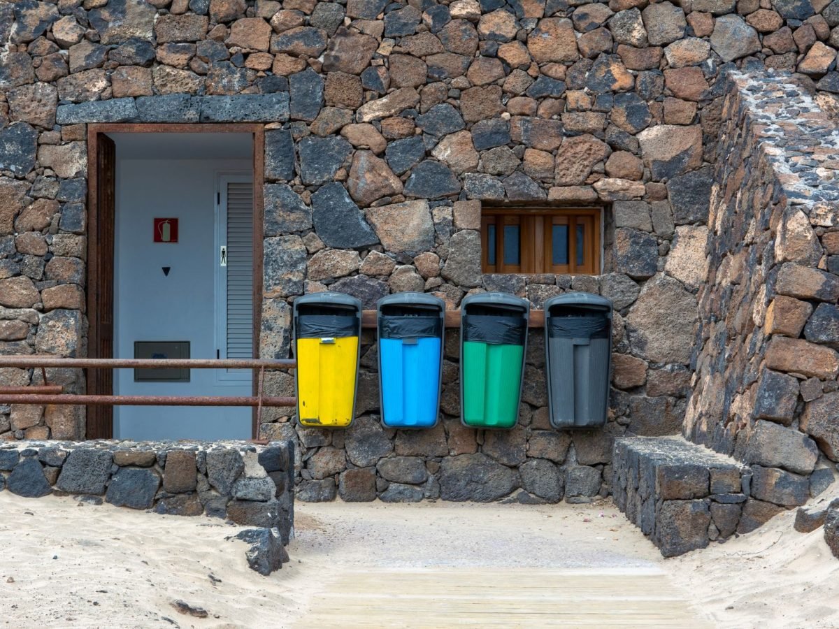 Colour-coded recycling bins lined up outside a building